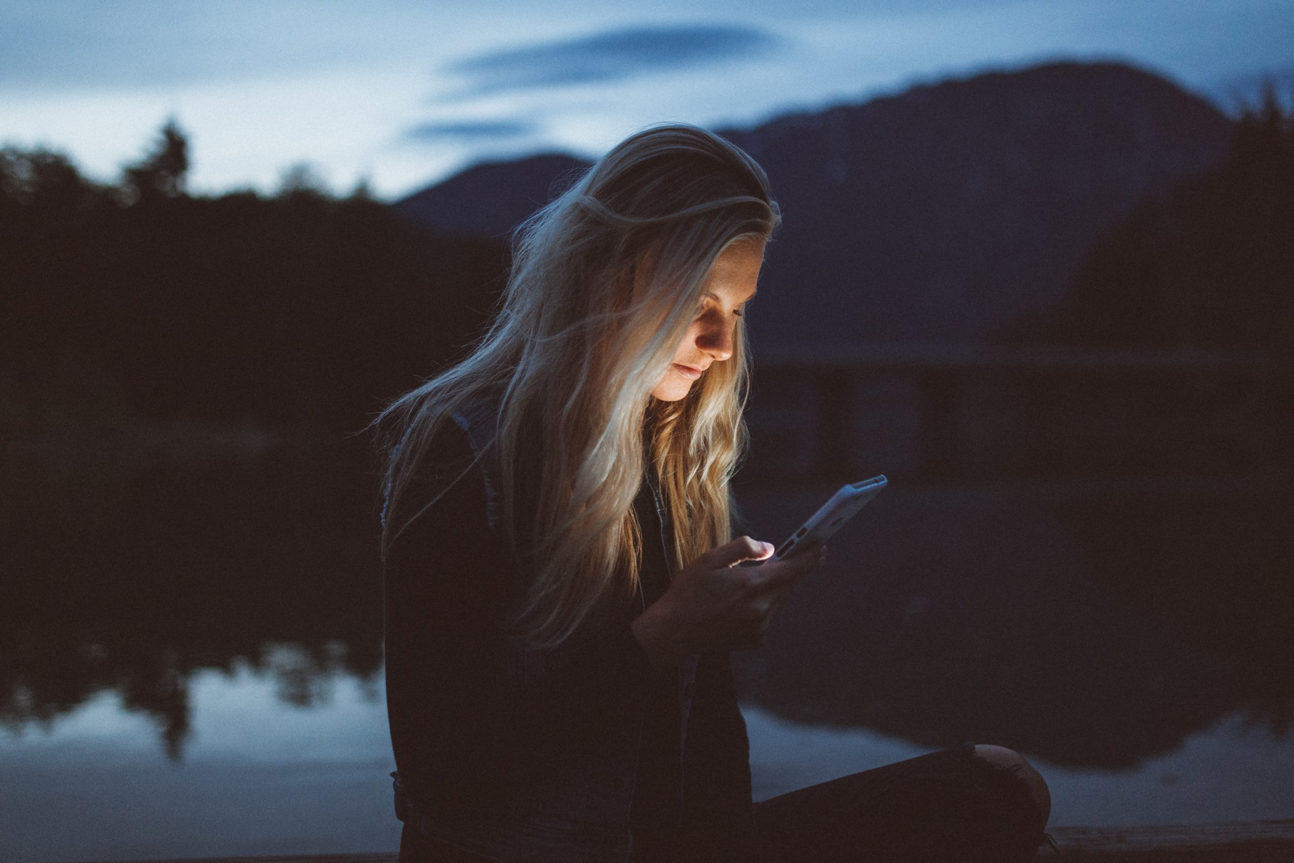 Photo of a woman at night reading her phone