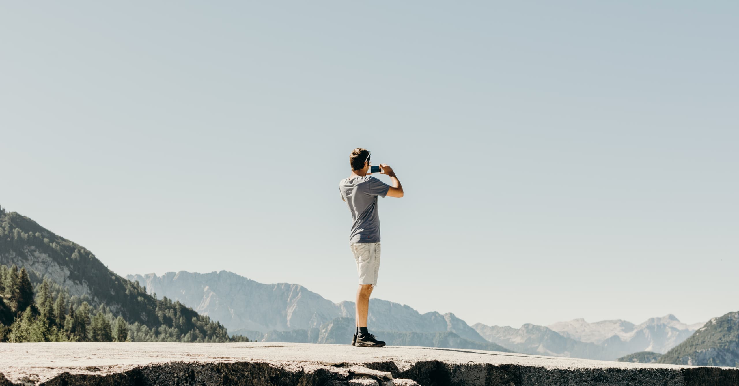 A man standing on top of a rock looking at the mountains.