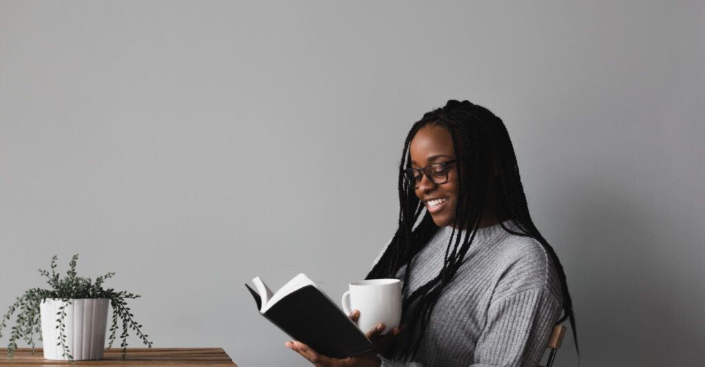Photo of a woman reading a book and drinking coffee